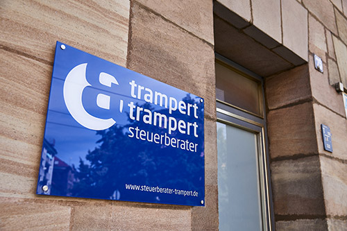 trampert & trampert steuerberater dunkelblaues Firmenschild Plexiglas mit Logo und Webadresse in Weiß, an Hauseingang an Sandsteinmauer, Aufnahme dynamisch schräg 